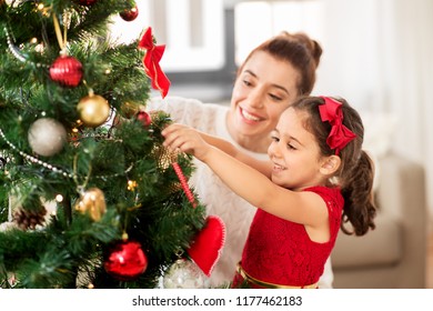 Family, Winter Holidays And People Concept - Happy Mother And Little Daughter Decorating Christmas Tree At Home