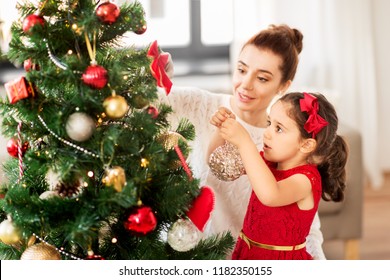 Family, Winter Holidays And People Concept - Happy Mother And Little Daughter Decorating Christmas Tree At Home