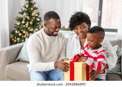 Family, Winter Holidays And People Concept - Happy African American Mother, Father And Baby Son Opening Gift Box At Home On Christmas