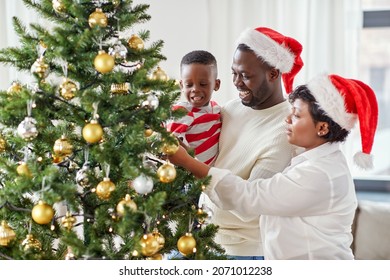 family, winter holidays and people concept - happy african american mother, father and little son decorating christmas tree at home on - Powered by Shutterstock
