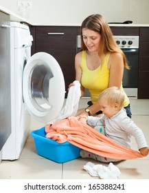 Family Woman Putting Clothes In To Washing Machine   At Home