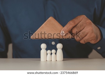 Family wooden peg dolls inside the wooden home, family day, warmth, happiness, planning property investment, health care and mental health, life insurance concepts.