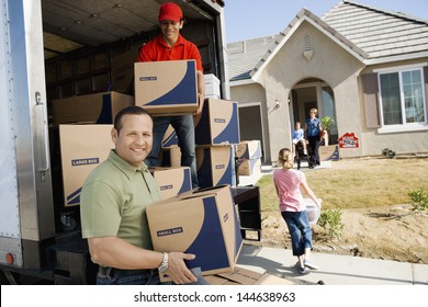 Family And Worker Unloading Delivery Van In Front Of A New House