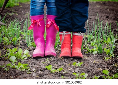 Family Works In The Garden. Mother And Kid In Rubber Boots . 