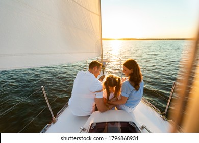 Family Yacht Sailing. Parents And Little Daughter Sitting Together On Sailboat Deck Hugging Enjoying Sea Trip. Back View, Free Space