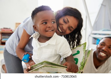 Family With Young Children Reading Book In Playroom Together