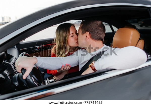 Family young couple kissing in the car standing in\
the Parking lot