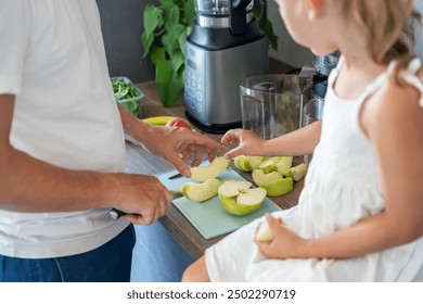 Family with a young father and his little daughter preparing fruit for a healthy juice or smoothie in home kitchen. High quality photo - Powered by Shutterstock