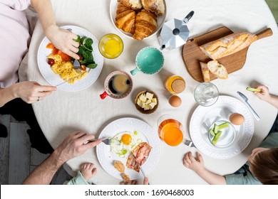 Family With Young Kids Having Healthy Breakfast With Different Cooked Eggs, Coffee. Flat-lay Of Plates With Food And People's Hands Holding Juice Over White Textile Round Table Background, Top View. 