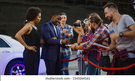 Famous African-American man and woman walking out of limo and posing for shoots and giving autographs on red carpet of celebrity event