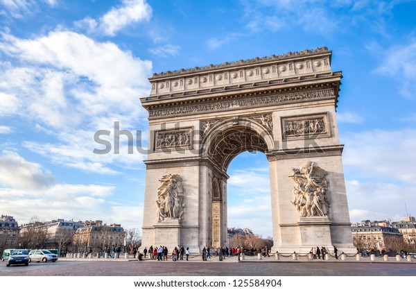 Famous Arc de Triomphe against nice blue sky  Arc\
de Triomphe monument at at the western end of the Champs-elysees\
road in Paris, France