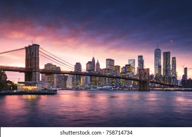 Famous Brooklyn Bridge In New York City With Financial District - Downtown Manhattan In Background. Sightseeing Boat On The East River And Beautiful Sunset Over Jane's Carousel.