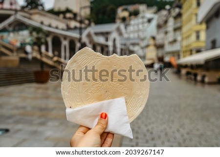 Famous Carlsbad wafer (CZ: lazenske oplatky) originated in 1867. Woman hand holding traditional Czech sweet cookie snack made in Karlovy Vary, famous spa city on UNESCO list.Tasty food background 