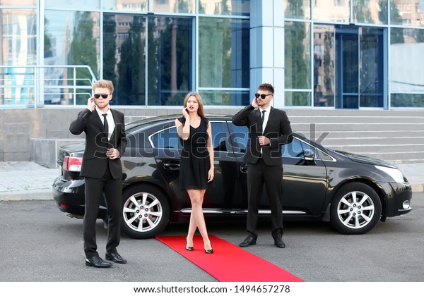 Famous\
celebrity with bodyguards near car\
outdoors