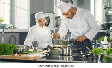 Famous Chef And His Female Apprentice Prepare Special Dish In A Modern Five Star Restaurant's Kitchen.