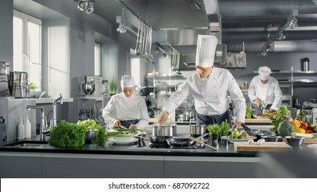 Famous Chef Works in a Big Restaurant Kitchen with His Help. Kitchen is Full of Food, Vegetables and Boiling Dishes. - Shutterstock ID 687092722