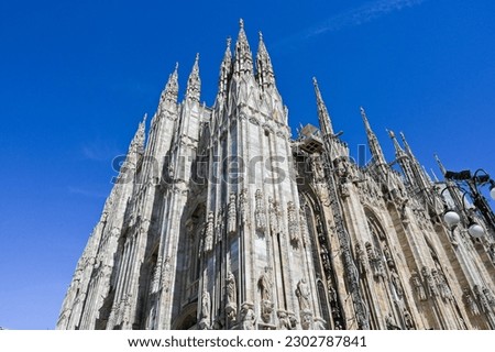 Famous church Milan Cathedral Duomo di Milano with Gothic spires and white marble statues. Top tourist attraction on piazza in Milan Lombardia Italy Wide angle view of old Gothic architecture and art