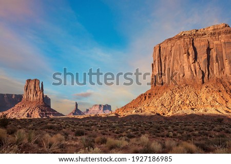 The famous cliffs Mittens in Monument Valley. The rocks - outcrops made of red sandstone. Bright multi-color sunset on the red stone valley. The concept of active, environmental and photo tourism