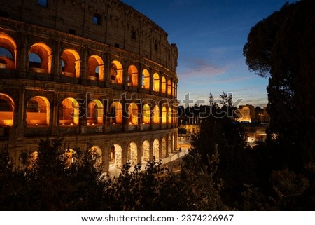Famous Colosseum at night in beautiful lighting. With orange window arches and a blue night sky.