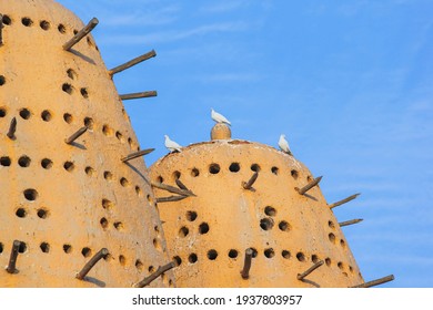 Famous Earthen Pigeon Towers With White Pigeon Flying Away In Katara Cultural Village Of Doha, Qatar