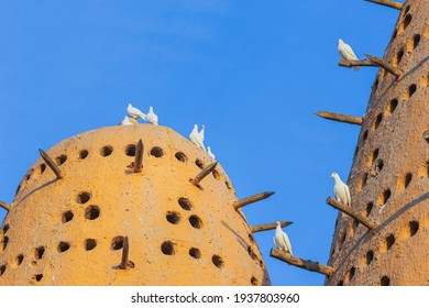 Famous Earthen Pigeon Towers With White Pigeon Flying Away In Katara Cultural Village Of Doha, Qatar