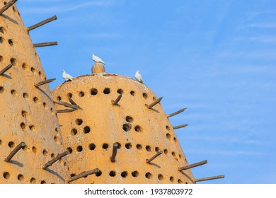 Famous Earthen Pigeon Towers With White Pigeon Flying Away In Katara Cultural Village Of Doha, Qatar