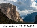 The famous El Capitan peak is scene from near the Tunnel View overlook with clouds and afternood light peeking through the clou cover, Yosemite National Park, CA