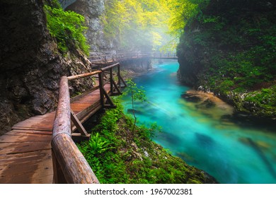 Famous foggy Vintgar gorge with wooden footbridge over the Radova river after summer rain. Popular hiking and touristic place, Slovenia, Europe