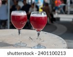 Famous fresh brewed red lambic kriek cherry beer served outside in Belgian beer festival in Durbuy,  special Belgian beer glass in sun lights, close up