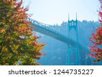 Famous gothic St Johns bridge across the Willamette River in Portland industrial area with arched support pillars surrounded by autumn colorful trees is a real pride of the Portland people