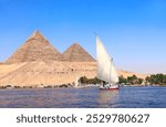 Famous Great Pyramids of Chephren and Cheops and traditional sailing boat felucca, Nile river, Egypt. A famous tourist attraction - sailing boat ride