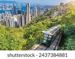 The famous green tram on the slope of Victoria Peak in Hong Kong passes, lifting visitors to the observation deck at the top.