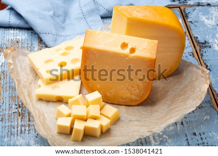 Famous hard cheeses, Dutch Gouda and French Emmentaler in pieces and blocks on paper