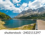 The famous lake named "Fedaia", in the Dolomites mountain chain, Italy. On the background the mountain named "Marmolada", with blue sky and white clouds.