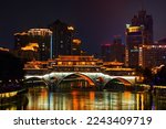 Famous landmark of Chengdu - Anshun bridge over Jin River illuminated at night with modern skyscrapers in background, Chengdu, Sichuan , China