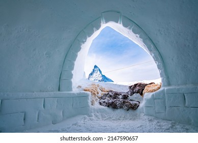 Famous Matterhorn Peak Against Sky Seen Through Igloo. Snow Covered Fur At Entrance Of Ice House. Interior Of Frozen Hut In Alpine Region During Winter.