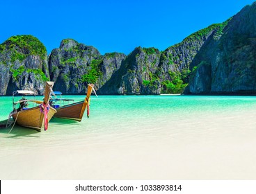 Famous Maya Bay beach at Ko Phi Phi Leh Island with two traditional longtail taxi boats mooring and steep limestone hills in background. Main Thailand tourist attraction, Krabi Province, Andaman Sea