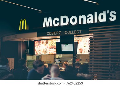 Famous McDonald's Restaurant, Poland - Nowy Sacz - November 25, 2017. Staff Prepares Meals For Release And Above Them The Illuminated Menu With Food Sets.