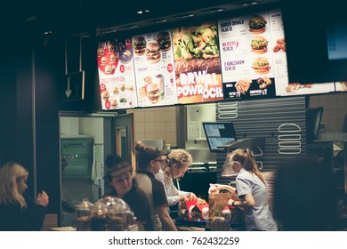 Famous McDonald's Restaurant, Poland - Nowy Sacz - November 25, 2017. Staff Prepares Meals For Release And Above Them The Illuminated Menu With Food Sets.