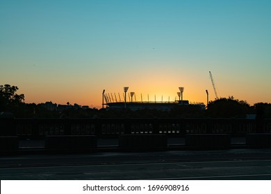 Famous Melbourne Cricket Ground Stadium Silhouetted By Bright Rising Morning Sun.