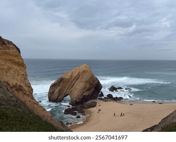 Famous natural arch rock formation at Praia de Santa Cruz Beach , Torres Vedras, Portugal.  Stone Oceanic Landforms. Beach cave. Bing Rock in a sandy beach - Powered by Shutterstock