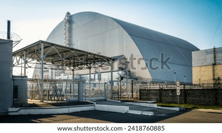 famous place nuclear power plant with a new dome and security gates against the blue sky in Chernobyl Ukraine in the afternoon in autumn