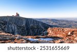 Famous place Snezne jamy on the  Czech-Polish border high in the Krkonose mountains during autumn golden sunset with observation tower and scenic panorama view to the rocky cliffs and old snow.