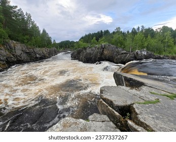 The famous powerful and wide Karelian waterfall Voitsky Padun in summer surrounded by rocks and greenery.