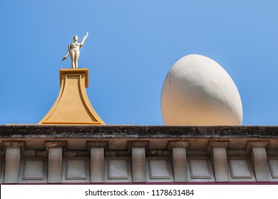 The Famous Salvador Dalí Theatre And Museum In Figueres, Catalonia, Spain, Europe. The Façade Is Topped By A Series Of Giant Eggs And Golden Figures.