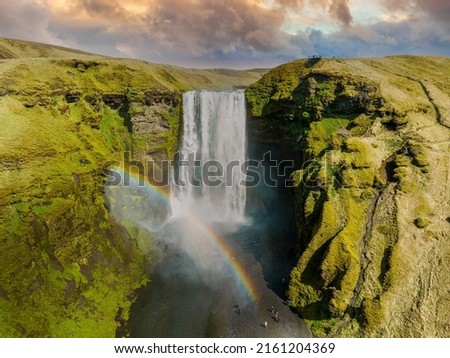 Famous Skogafoss waterfall with a rainbow. Dramatic Scenery of Iceland during sunset. Majestic Skogafoss Waterfall in countryside with colorful sky aerial scenic view.