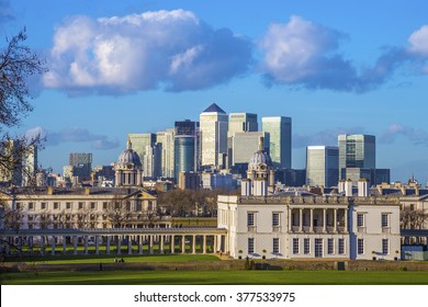 The Famous Skyscrapers Of Canary Wharf And London's National Maritime Museum Taken From Greenwich Park On A Sunny Day With Blue Sky And Clouds - London, UK