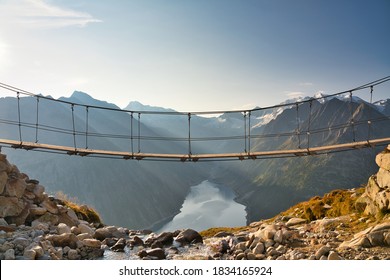 Famous suspended bridge in the austrian alps (Zillertal) with a view of the lake Schlegeis (Schlegeisspeicher) and the surrounding mountains during sunrise. Located near the the popular Olperer hut.