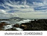 The famous Table Mountain with dramatic clouds in the Western Cape, South Africa as seen over the rocks in Table Bay