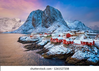 Famous tourist attraction Hamnoy fishing village on Lofoten Islands, Norway with red rorbu houses. With falling snow in winter on sunrise